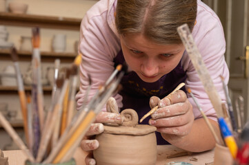 cute, emotional fair girl sculpting from clay in a pottery workshop, clay crafts and art,...