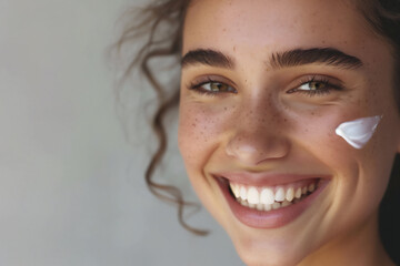 Skin care concept - beauliful young girl laughing, cream drop on the cheekbones