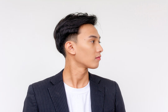 A slim young asian man with boyish looks facing to the right. Isolated on a white background.