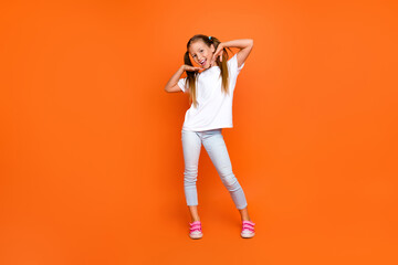 Fototapeta na wymiar Full length portrait of lovely cheerful girl have good mood empty space ad isolated on orange color background