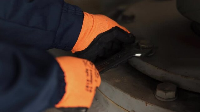 screwing nut, Twist mechanic, Nut tightening. Using wrench laborer industrial plant either tightens loosens nut on bolt.