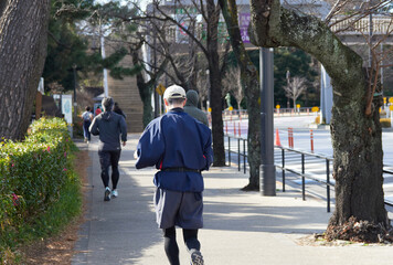 冬の東京の皇居外苑の道でランニングする人々の姿