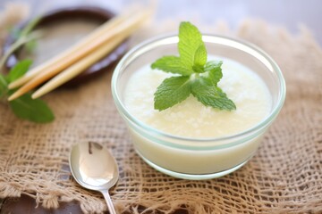 Obraz na płótnie Canvas vanilla bean pudding in clear bowl, mint sprig on top