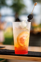 A refreshing summer cocktail with a blackberry and blueberry garnish on a skewer.