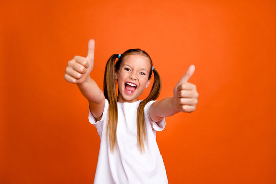 Photo portrait of cute little lady thumb up excited good job rate quality wear trendy white garment isolated on orange color background