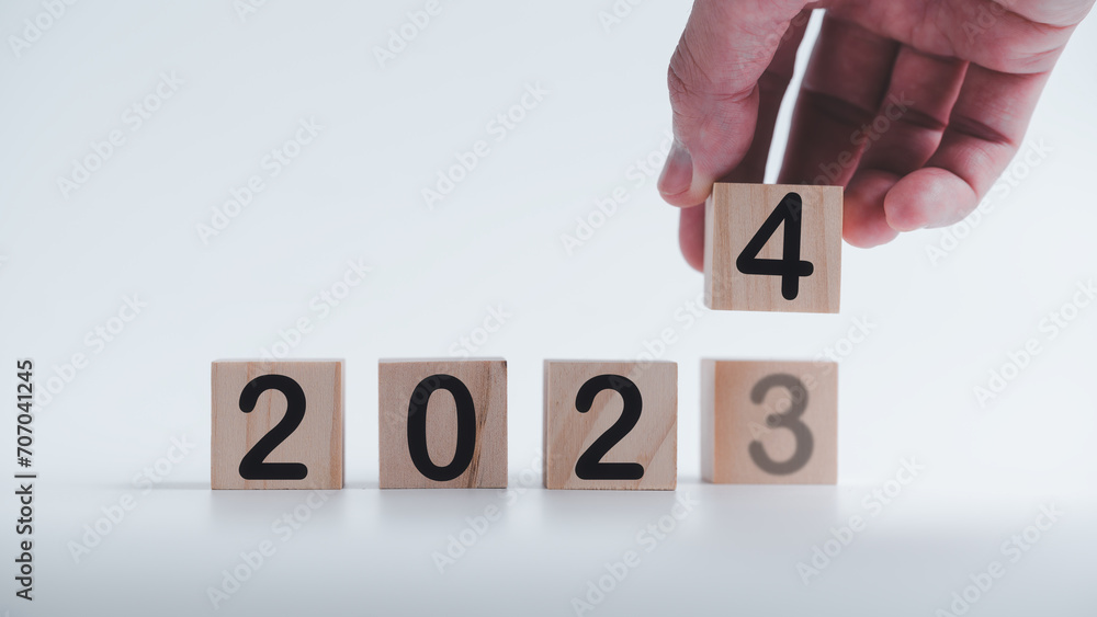 Poster hand holding wooden cubes with the text 2023 2024 over background to change or translated from 2023 
