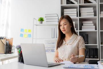 Working with finance and calculator in bank office, Asian female accountant working with laptop and financial documents in office