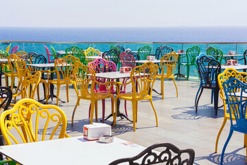 Colorful chairs in the restaurant with a view of the sea and the old town. Beautiful top view of...