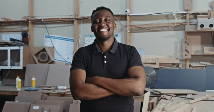 Young African male poses with arms folded in carpentry factory 