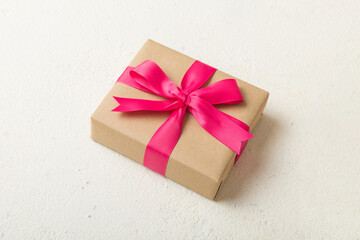 Wrapped christmas or other holiday handmade present in craft paper with colored ribbon. Present box, decoration of gift on table, top view with copy space