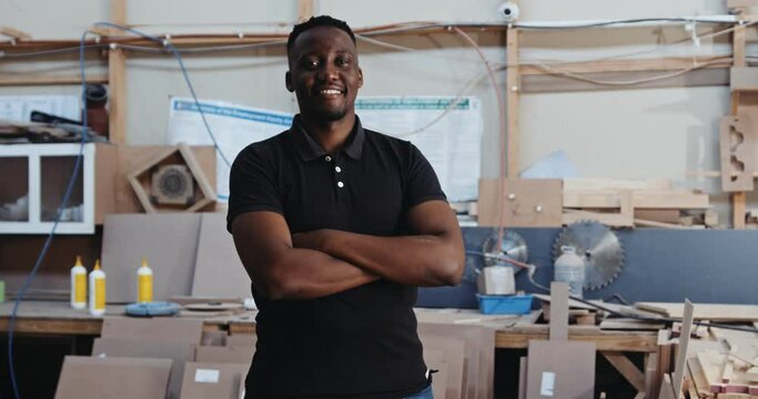 Happy African male with folded arms poses for a photograph in workshop 