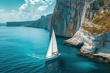Zelfklevend Fotobehang sailboat floating on sea with rocky cliff against sky on sunny day © Hugo