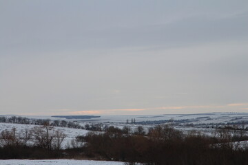 Obraz premium A snowy landscape with trees and a rainbow in the sky