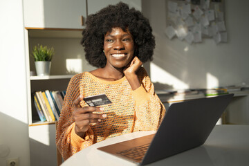 Thoughtful happy woman online shopping with credit card and laptop 