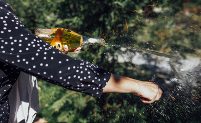 Young woman opens a bottle of sparkling wine by the knife