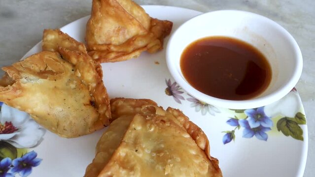 Samosa with tamarind sauce or chutney. A samosa or singara is a fried or baked pastry with a savory filling, including ingredients such as spiced potatoes, onions, and peas. Uttarakhand India.