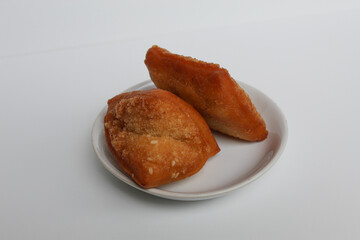 Odading or Bolang-Baling or Pillow Cake, sweet fried bread with sesame seed on top, from Indonesia. On a small plate isolated on background