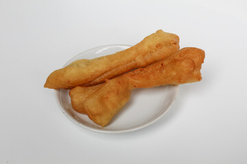Cakwe or cakue, fried savory cake from Indonesia, on small white plate, isolated on white background