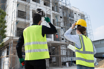 Back Caucasian engineer man and woman working with holding hard hat at construction site	