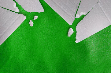 pieces of crushed white styrofoam atop a rough-textured shiny green surface