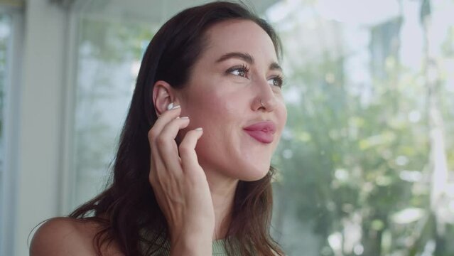 Close up of young woman wearing earphones calling her friend indoors
