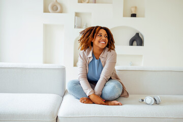 African american millennial girl, contented and happy, sit on comfortable sofa in cozy modern light...
