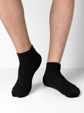 Male feet wearing black cotton socks on white background