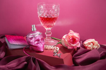 pink still life with perfume bottle in form scull and glass of wine