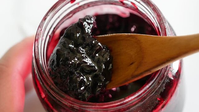 瓶に入ってる甘酸っぱいハスカップジャムをスプーンですくうクローズアップ動画。左から右へ。