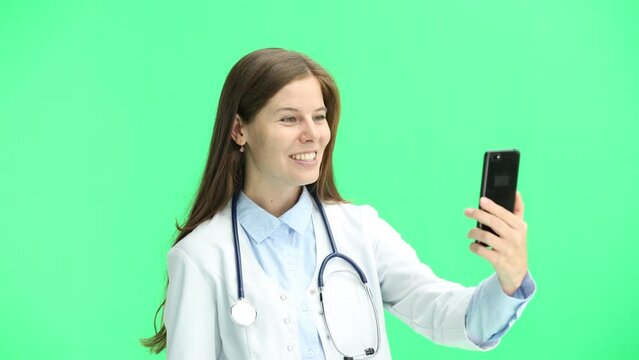 Female doctor, close-up, on a green background, with a phone
