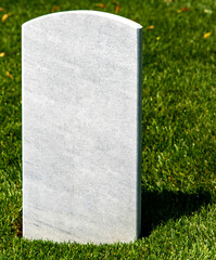 Vertical photo of a white tombstone on a grassy lawn at Arlington National Cemetery, a military...