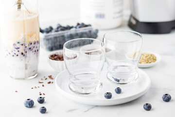 A blender cup full of healthy ingredients to make a blueberry protein smoothie.