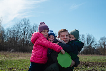 Smiling father and children outdoors spending time together. Child girl is holding a frisbee. Concept of childhood, fatherhood