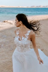 Fototapeta na wymiar bride in dress on beach, Happy young bride woman in white dress running, have fun on clean sandy beach waves of a sea or ocean on sunset, summer shooting near a water