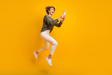 Fototapeta na wymiar Photo of funky crazy cool girl wearing stylish clothes running empty space reading social media isolated on yellow color background