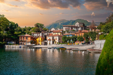 Fototapeta na wymiar Golden Hour Serenity at a Tranquil European Lakeside Village with Moored Boats, Italy