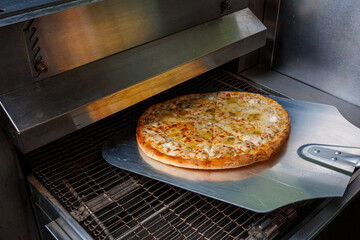 Woman putting baking sheet with pizza in oven