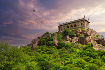 Fototapeta na wymiar Majestic Historical Palace on Rugged Hill Amidst Lush Greenery, Bird in Flight, Purple Sky