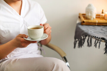 Happy lovely young female health worker laughing sincerely while holding cup of hot tea