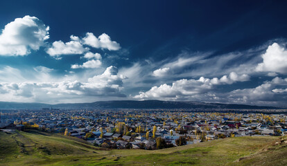 Panorama of the autumn city under a blue sky with clouds, captured from a high vantage point. Jalal-Abad, Kyrgyzstan
