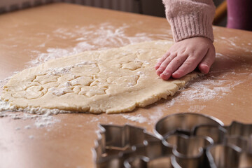 Girl's hands hold a cookie cutter and apply it to the dough. Side view. Home cooking of biscuits....