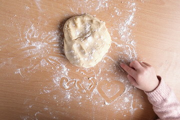 Hearts drawn by a child's hand in flour on the table while making cookies