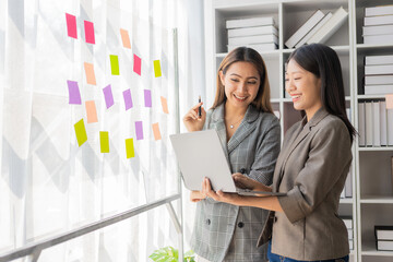 Asian businesswoman is discussing a new business project on a tablet. In a meeting, two people discuss investment projects on data charts and planning strategies. About new business