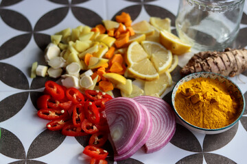 Fire cider chopped ingredients on grey tiled background. Top view photo of turmeric, ginger, pepper, garlic, onion and lemon. 