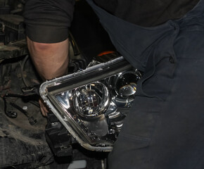 The car mechanic installs the lens in the headlight housing. The concept of a car service....