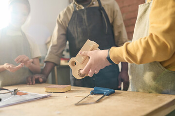 Close up of young boy holding wooden toy model in carpenting workshop for children, copy space