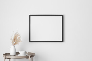 Black frame mockup on the wall with a pampas decoration.