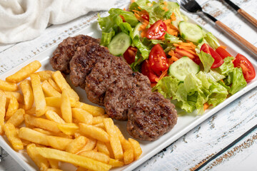 Grilled meat balls. Grilled meatballs with salad and fries on a white background. Close up