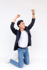 Obraz premium A young man pumped up and celebrating while sliding on his knees. Concept of exhilaration. Kneeling whole body shot Isolated on a white background.