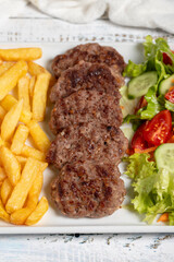 Grilled meat balls. Grilled meatballs with salad and fries on a white background